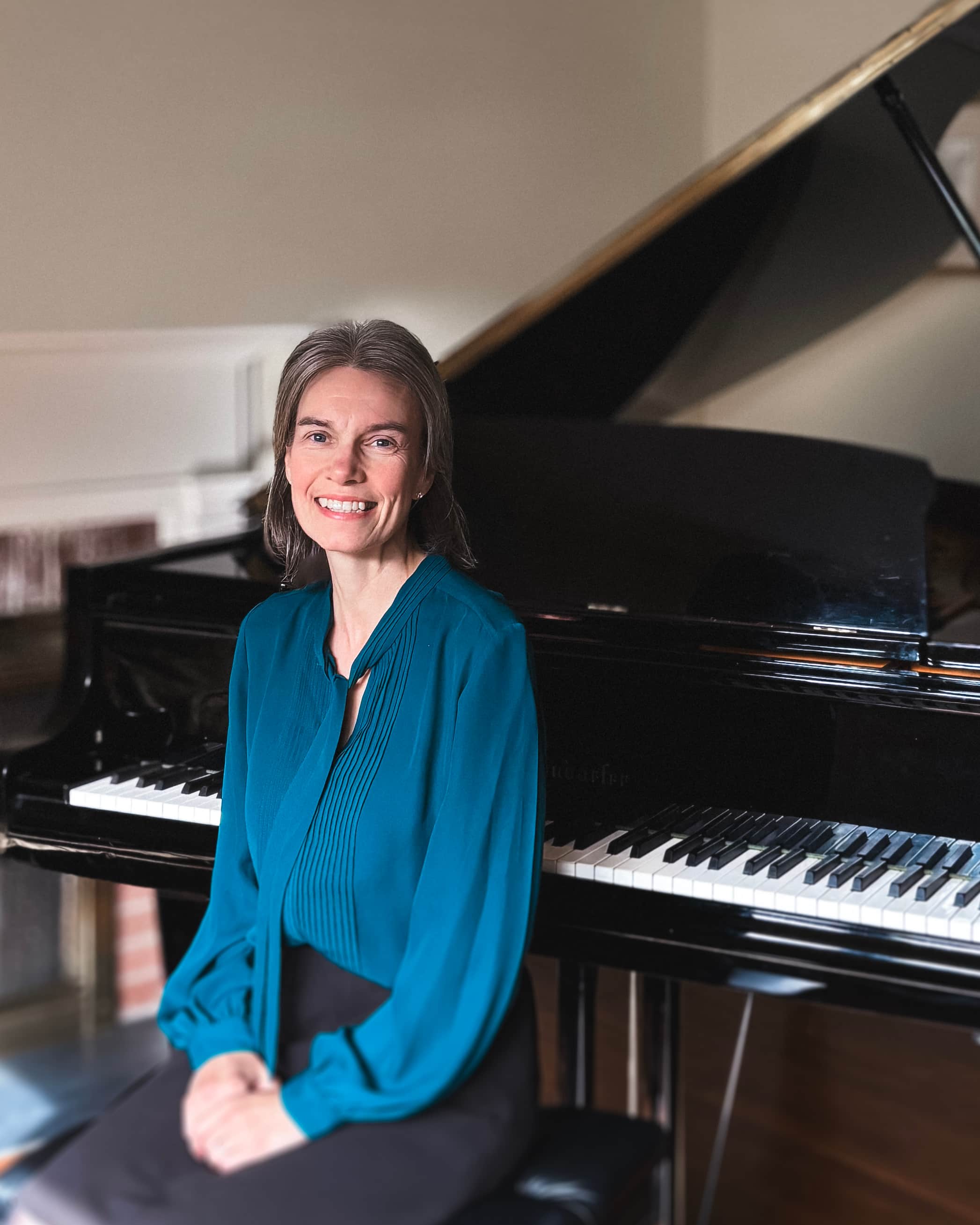 Julie Hague in front of a grand piano.