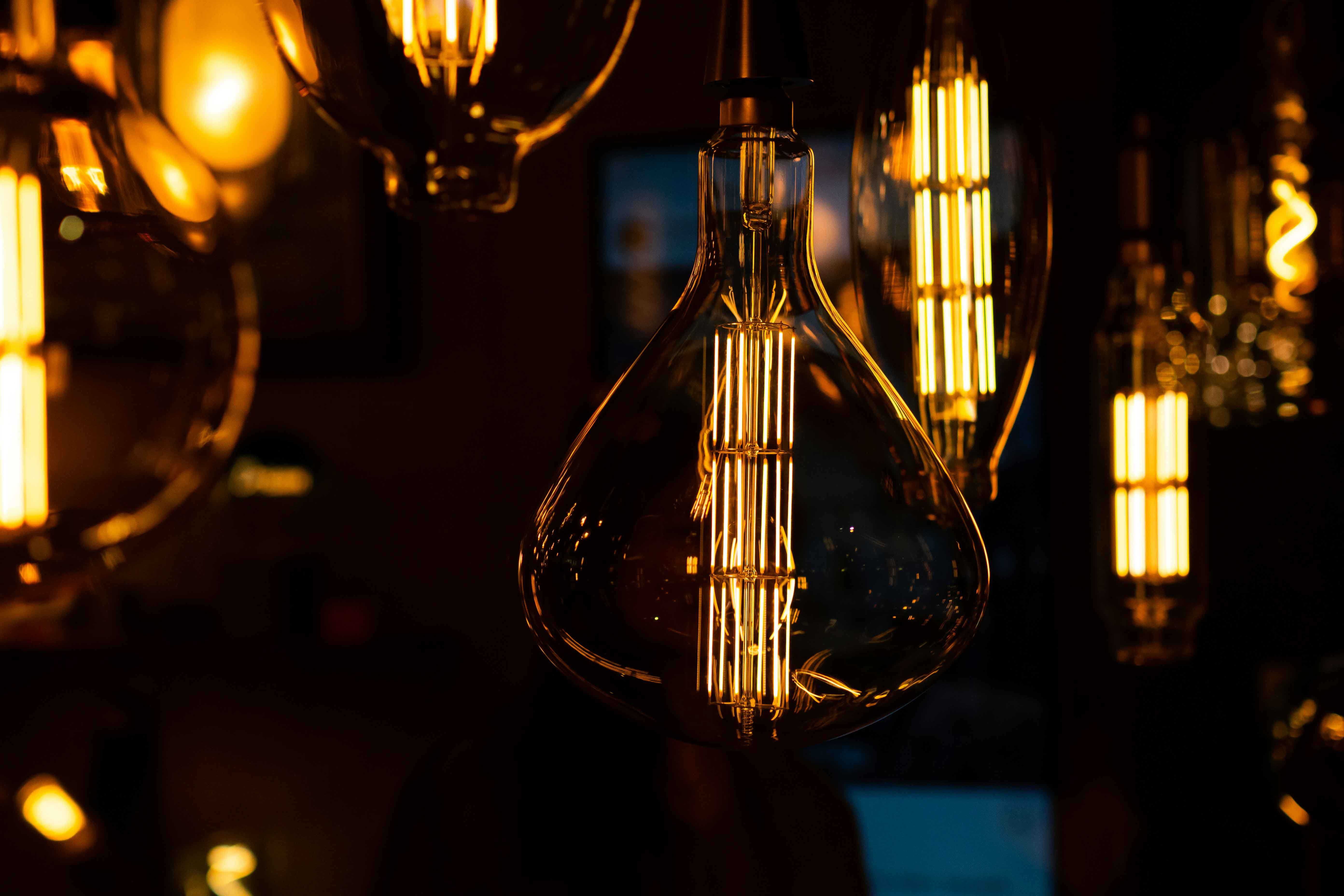 Mehrere dekorative, warm leuchtende Glühbirnen mit sichtbaren Filamenten vor dunklem Hintergrund.