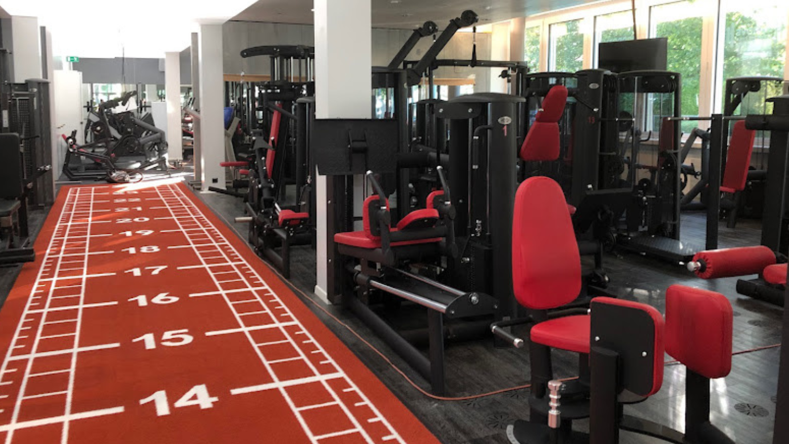 Fitnessbereich mit modernen Trainingsgeräten und roter Sprintbahn im MyMove Fitness Glattbrugg