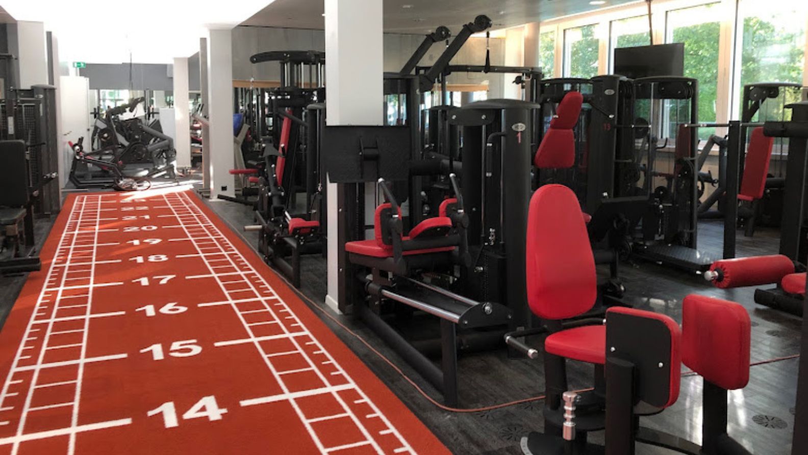 Trainingsbereich mit modernen Kraftgeräten und roter Sprintbahn im MyMove Fitnessstudio Glattbrugg