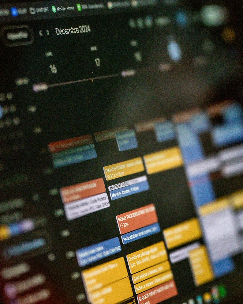 Capture d'écran floue d'un calendrier numérique affichant des événements colorés pour décembre 2024.