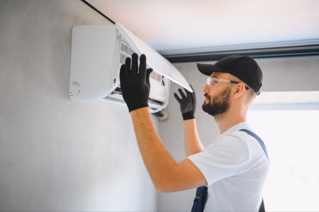 Technician repairing an air conditioning unit on a wall.