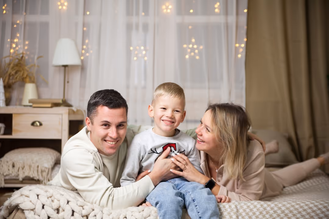 A happy family smiling and relaxing in a comfortable home environment, indicating the benefit of a well-maintained HVAC system - AC thermostat calibration