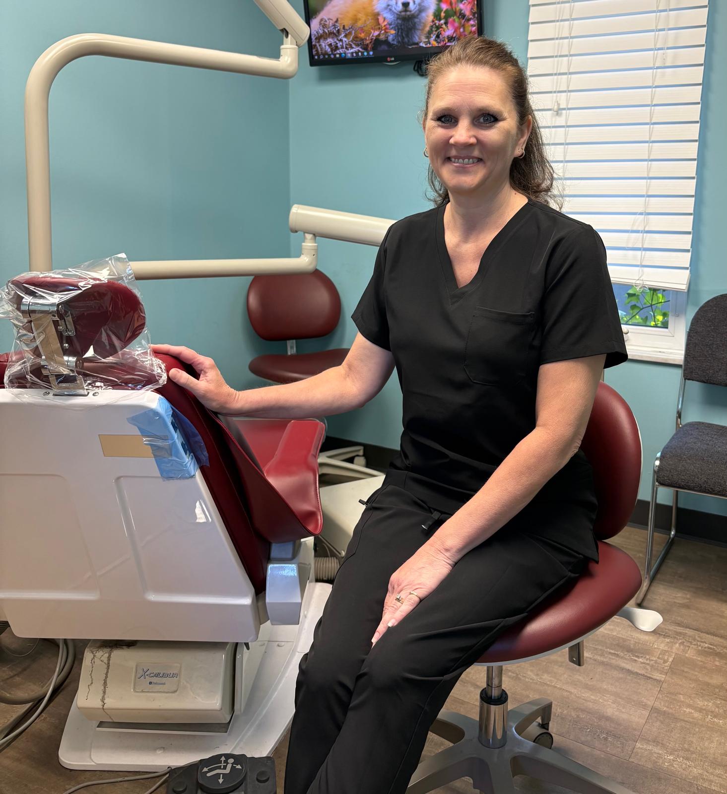 Dental professional in black scrubs smiling in examination room
