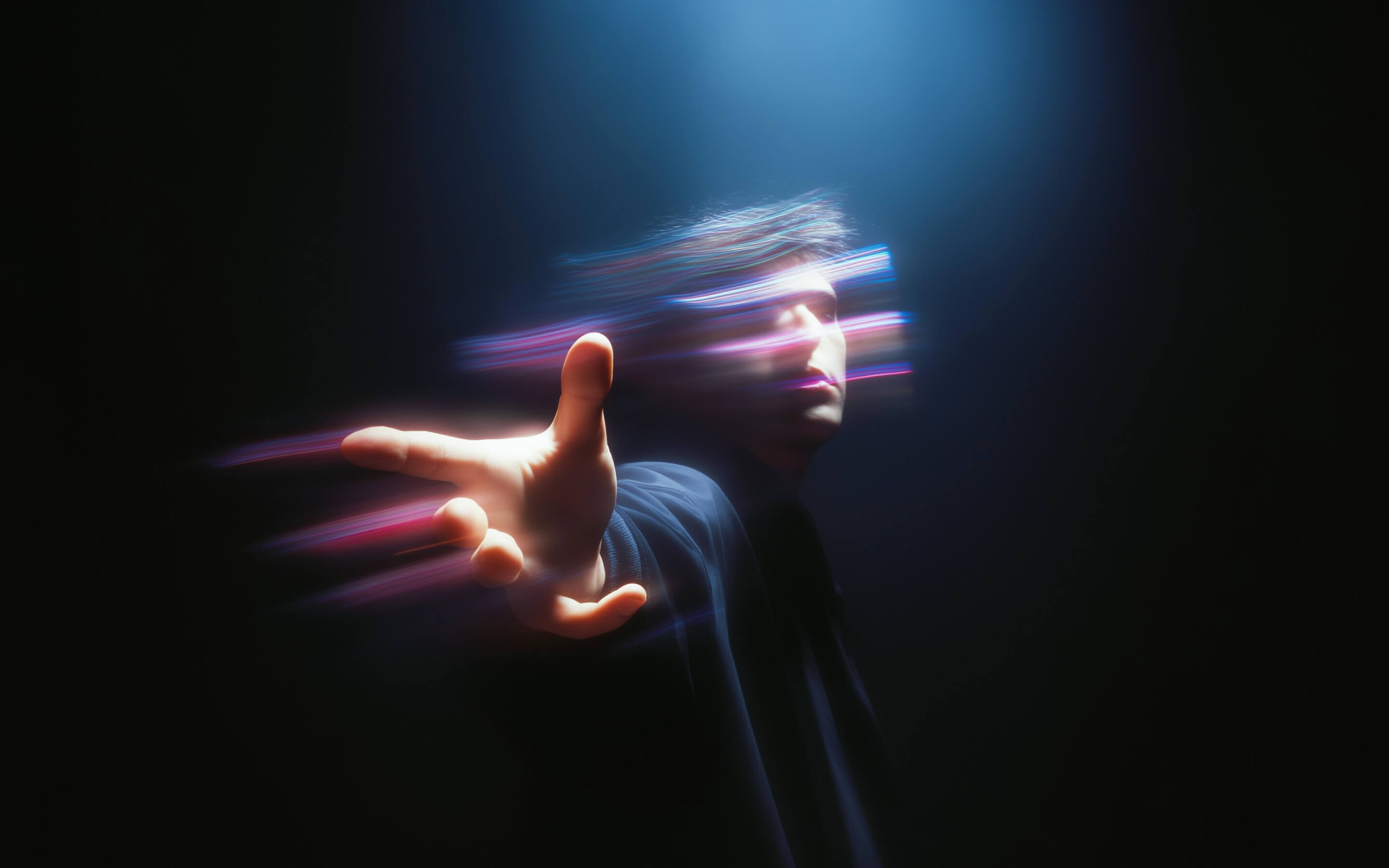 Person reaching forward with outstretched hand and their face blurred with colorful light streaks on a dark background.