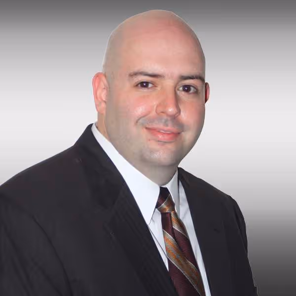 Bald professional in black suit and striped tie smiling