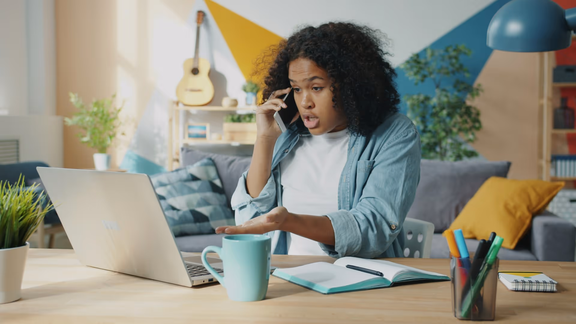 Woman working from home, talking on phone with laptop and notebook