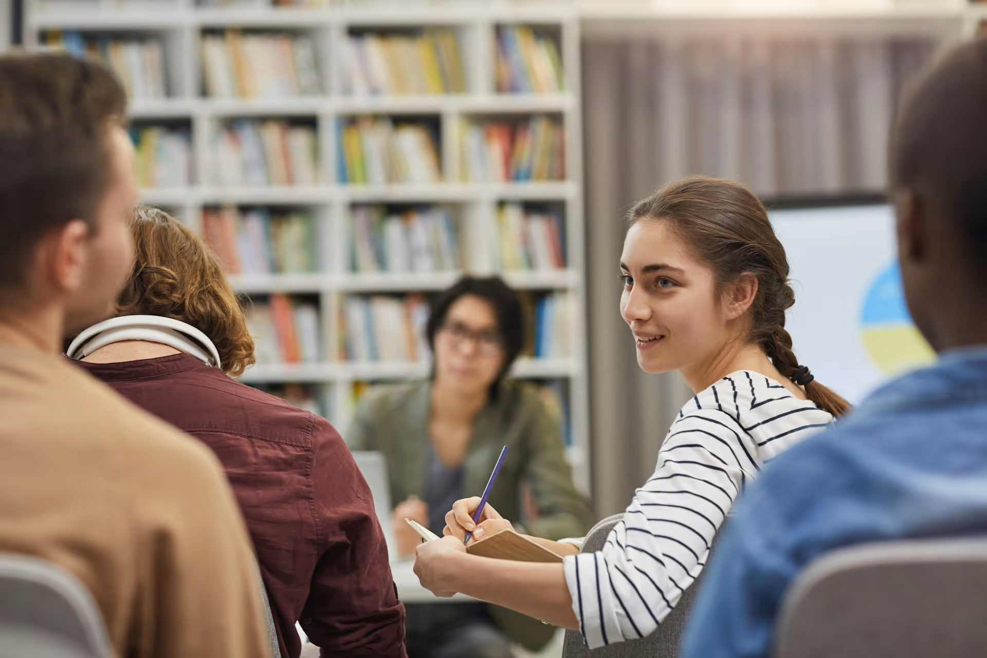 Students studying together in library with bookshelves in background