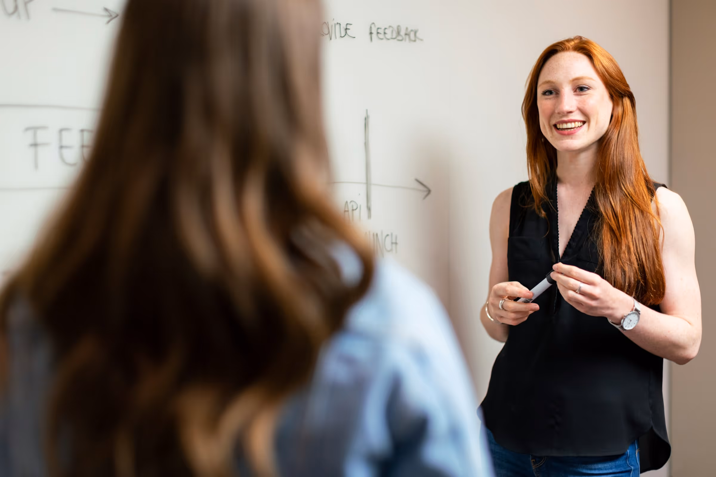 Smiling instructor giving presentation near whiteboard with diagrams