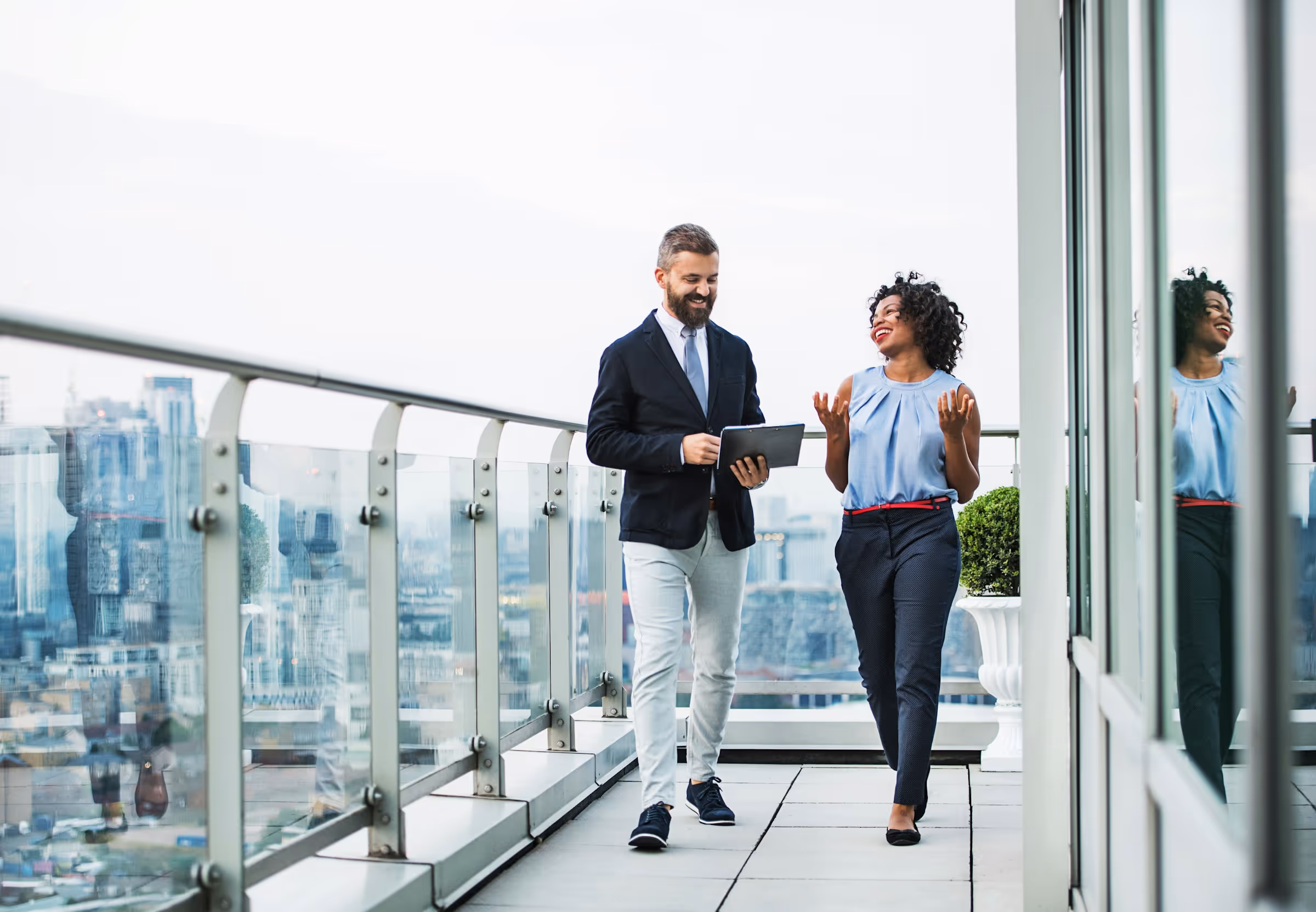 Business colleagues walking and talking on modern office balcony with city view