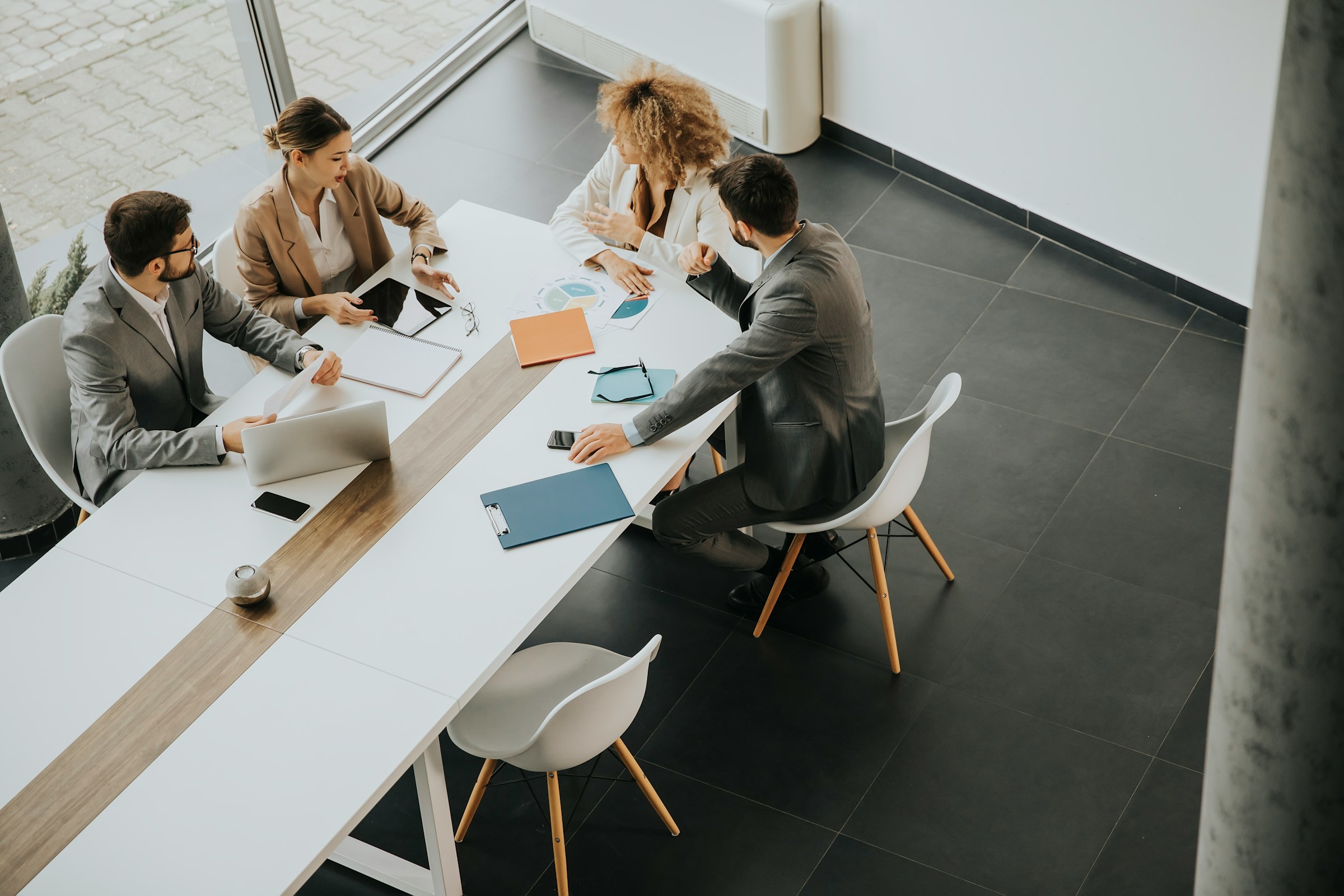 Four business professionals in meeting discussing documents at modern office table