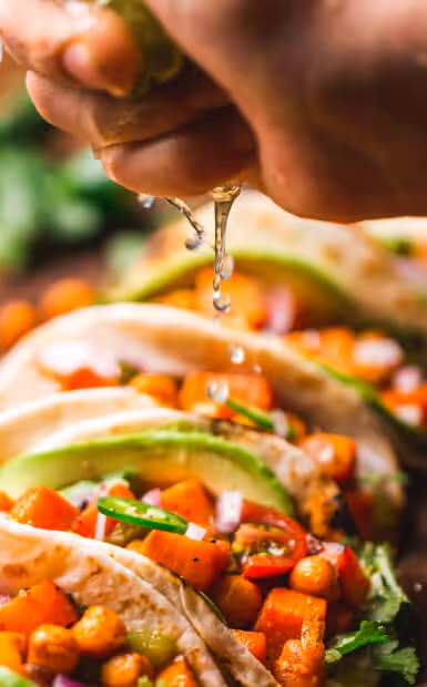 Tacos that someone is squeezing lime onto