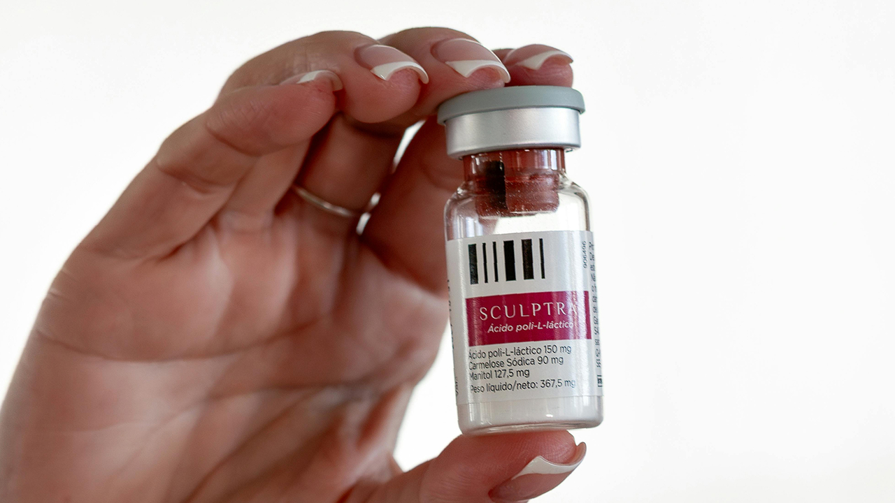 Close-up of hand holding Sculptra vial used for collagen-stimulating facial rejuvenation.