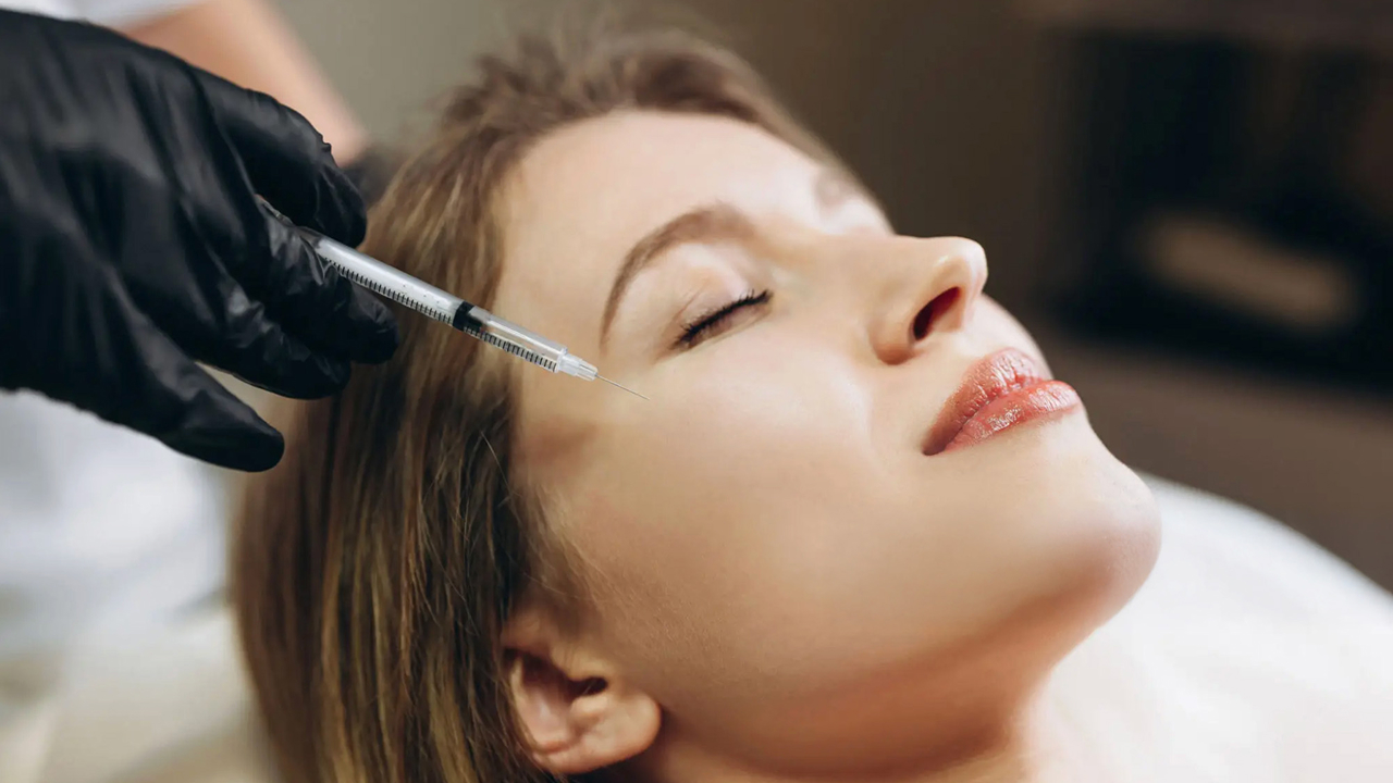 Aesthetic injector applying dermal filler to cheek area to restore volume and enhance contours.