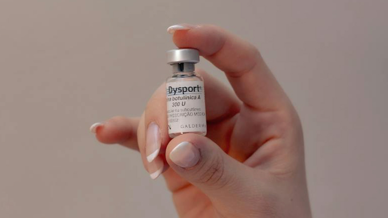 Hand holding Dysport vial before wrinkle-smoothing injectable treatment.