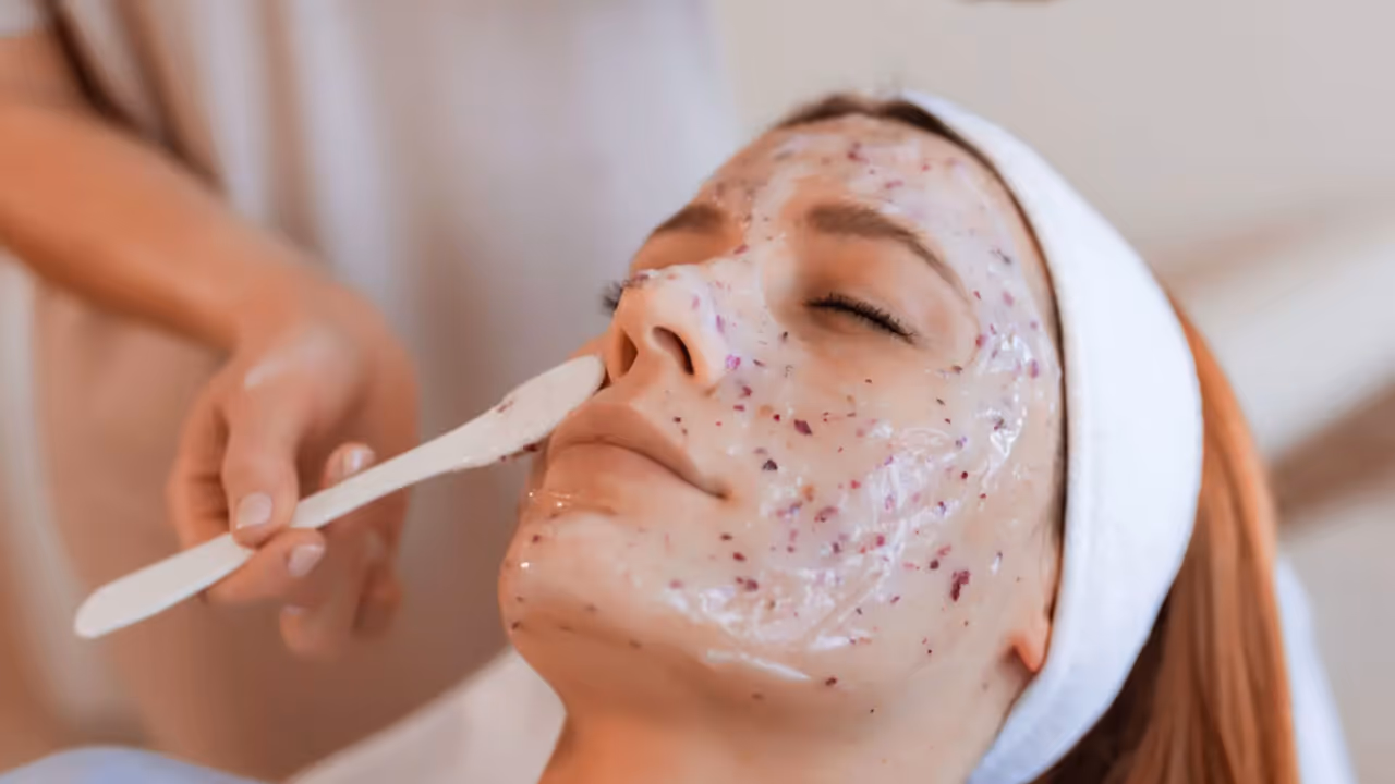 Woman receiving chemical peel treatment applied with brush to exfoliate skin.