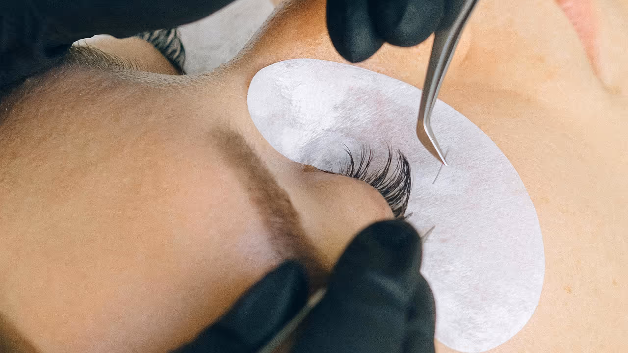Close-up of lash technician applying individual eyelash extensions for added length and volume.