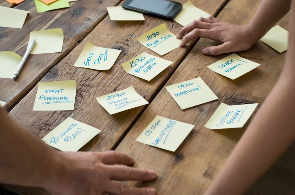Hands arranging sticky notes on a desk.