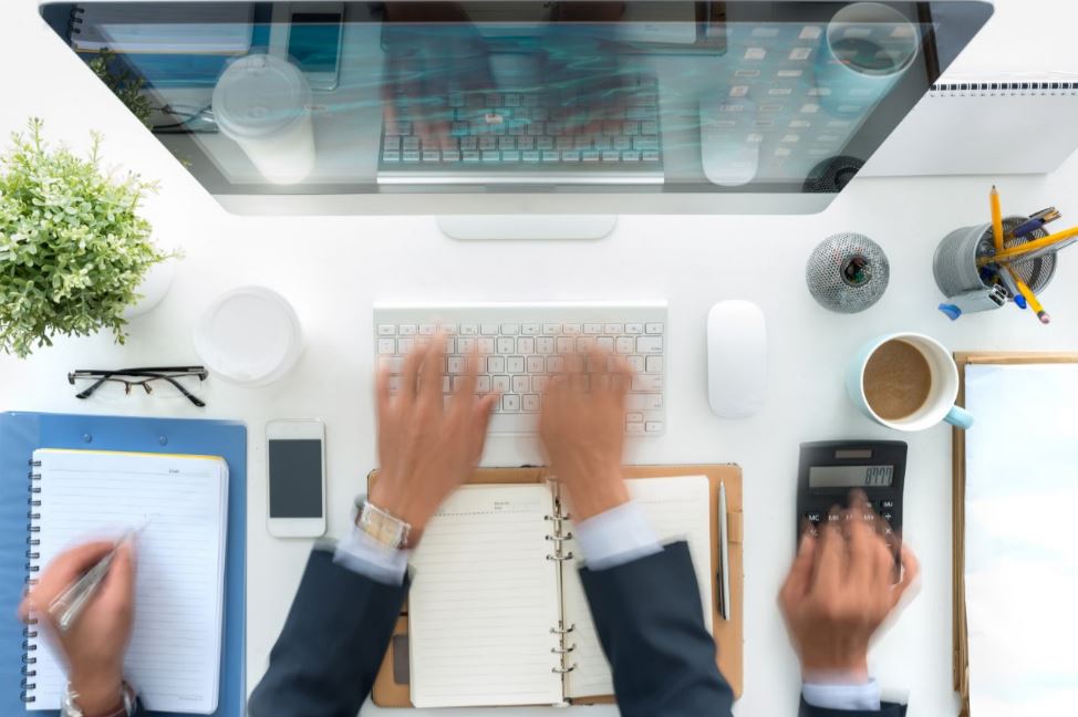 Multiple sets of hands working at a computer.