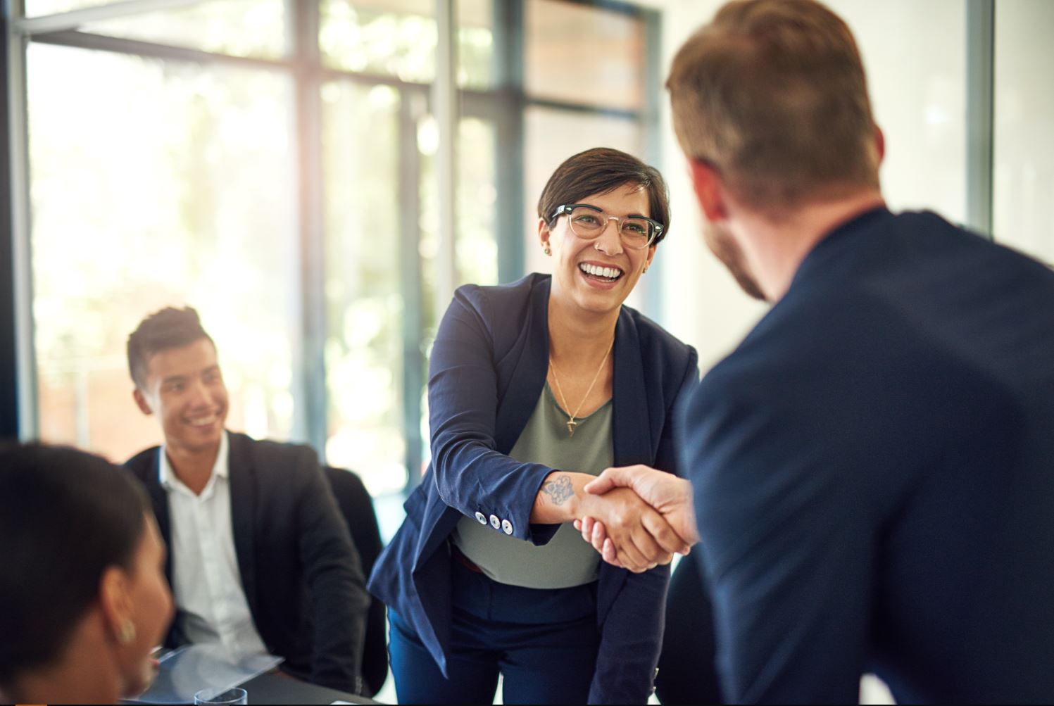 Business woman shaking hands with a man at a meeting.
