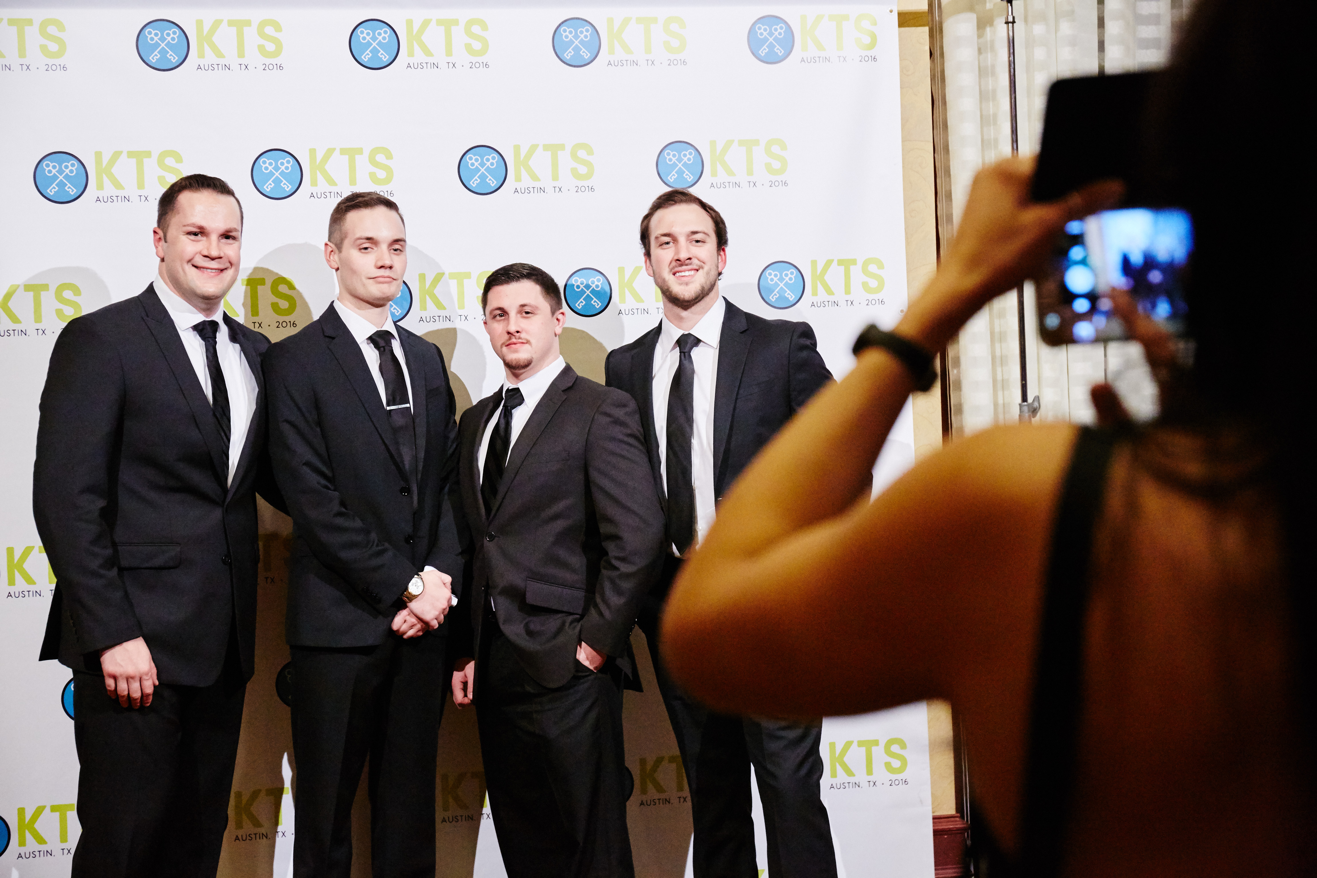 Four professionally dressed men at a business event.