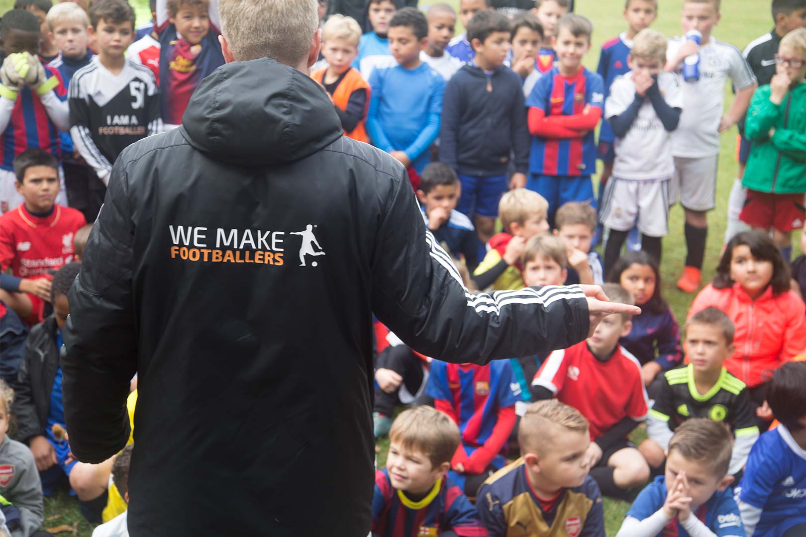 Coach addressing a large group of children at a football event