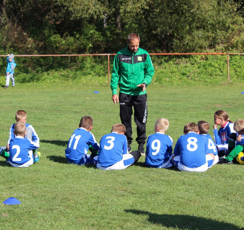 Coach talking to young players sitting on the grass