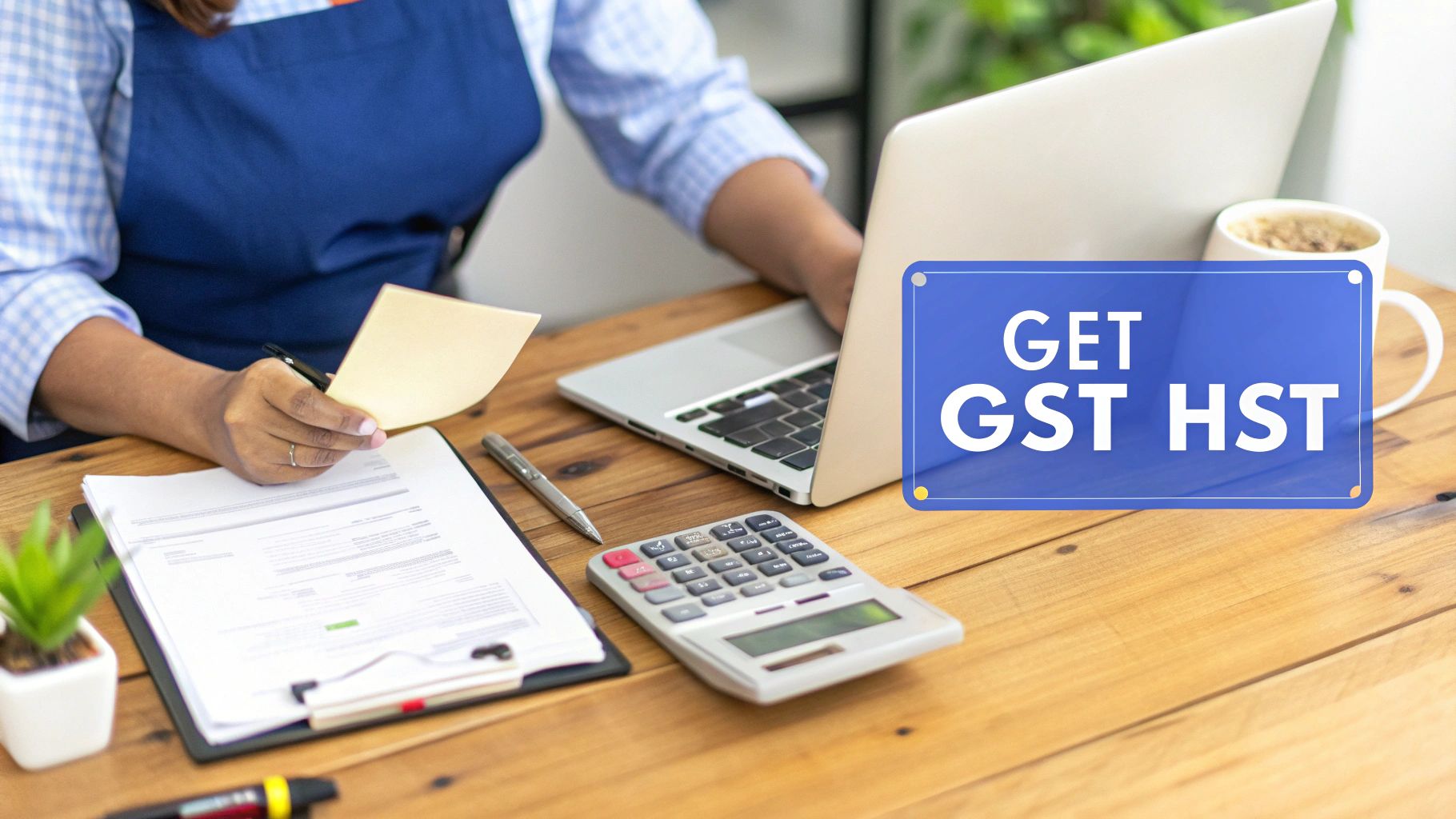 Person working on tax documents and laptop, with a prominent 'GET GST HST' sign on the desk.