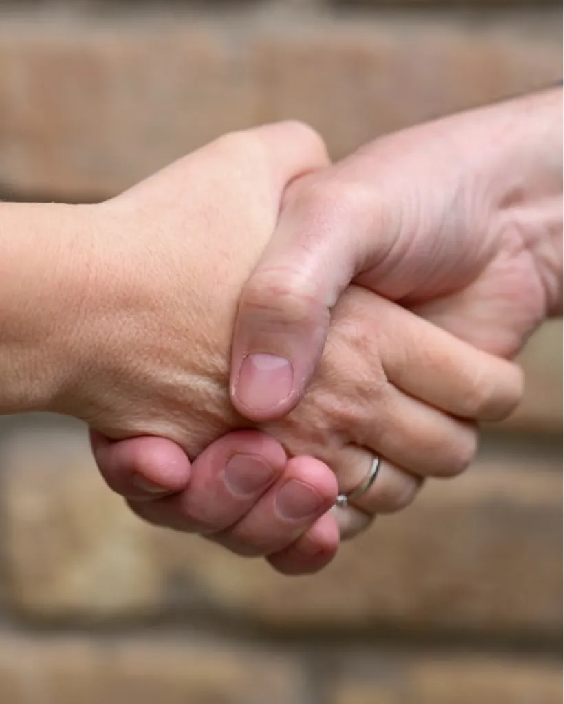 Black and white photograph of two people shaking hands, conveying partnership.