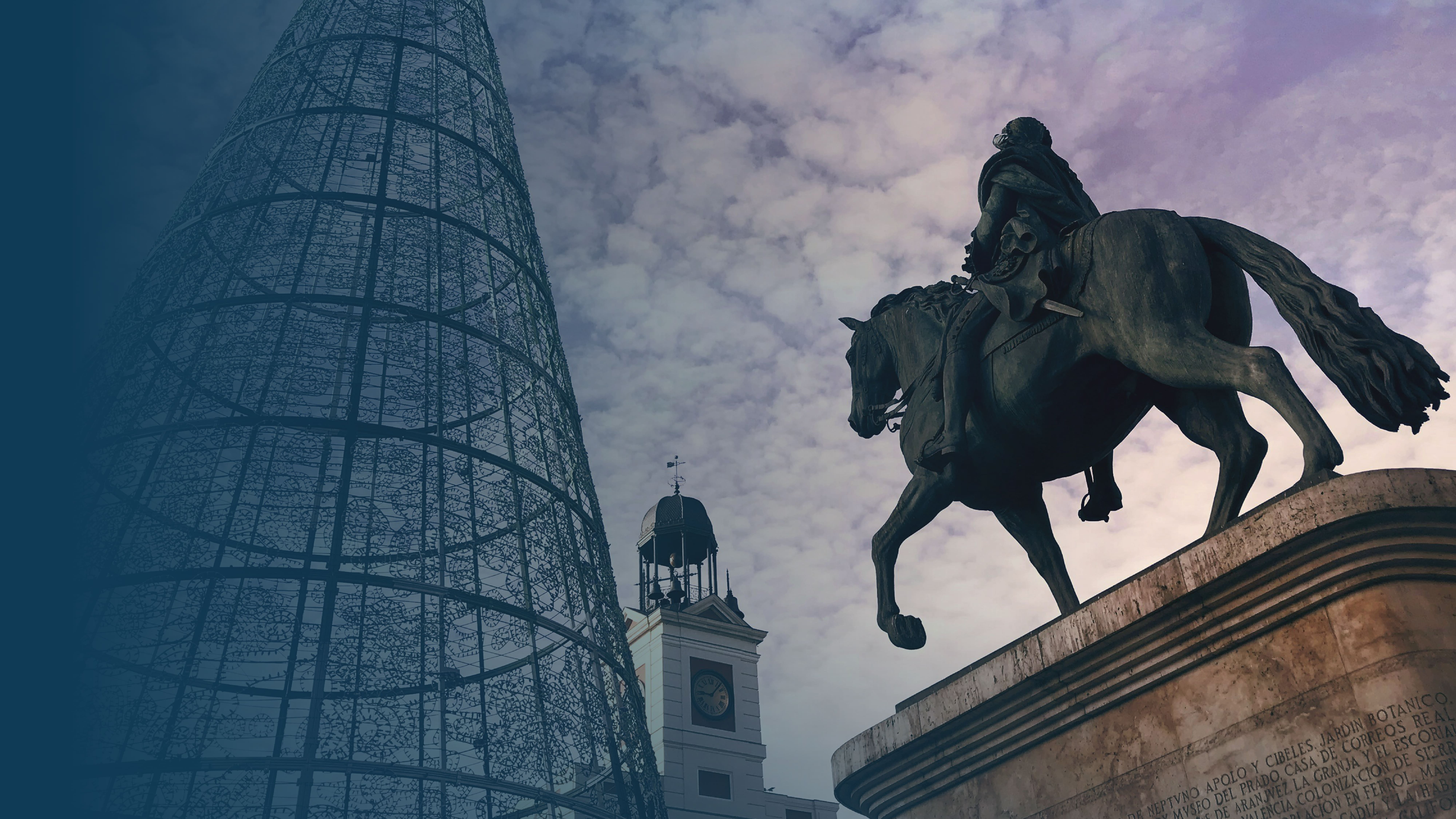 Estatua ecuestre recortada contra un cielo nublado cerca de una gran estructura metálica cónica y un edificio con torre de reloj.