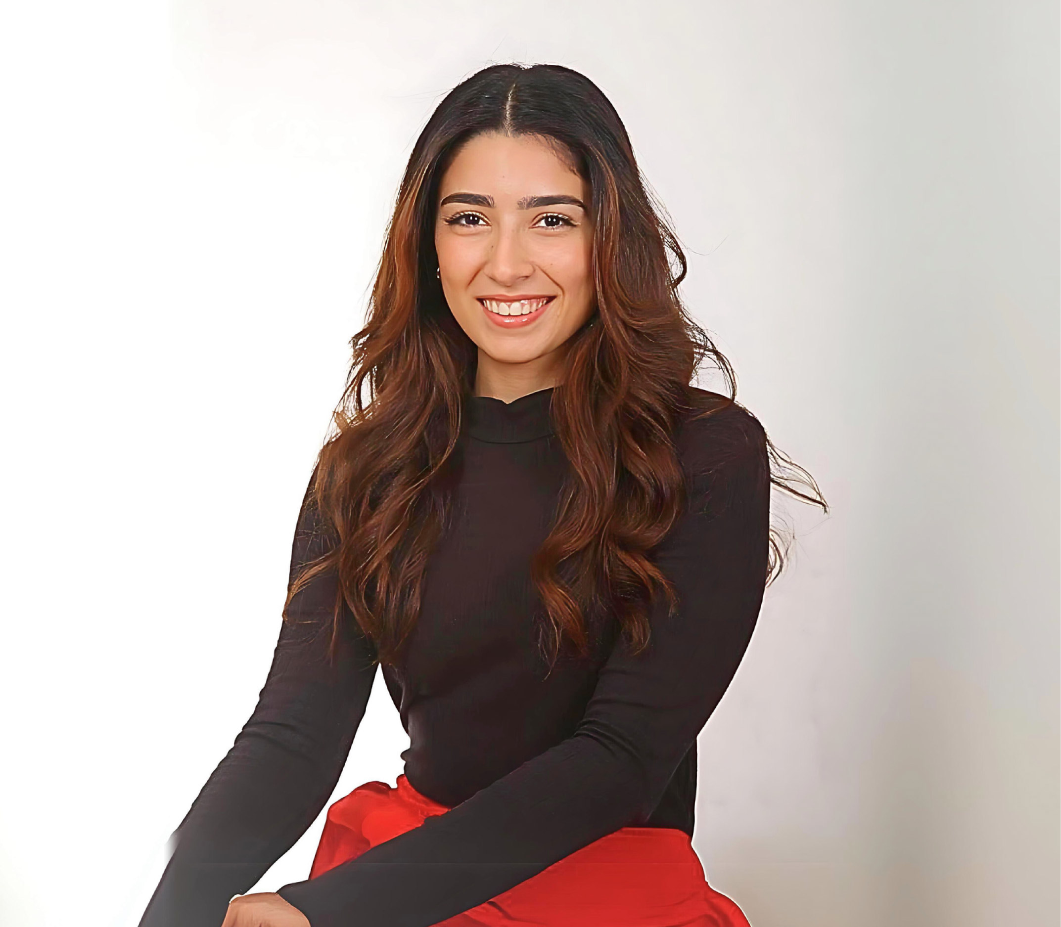 A female student in a dishdasha, with a white background.
