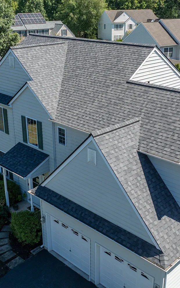 Aerial view of a suburban house with a gray asphalt shingle roof, parfectly cleaned after a repair job.
