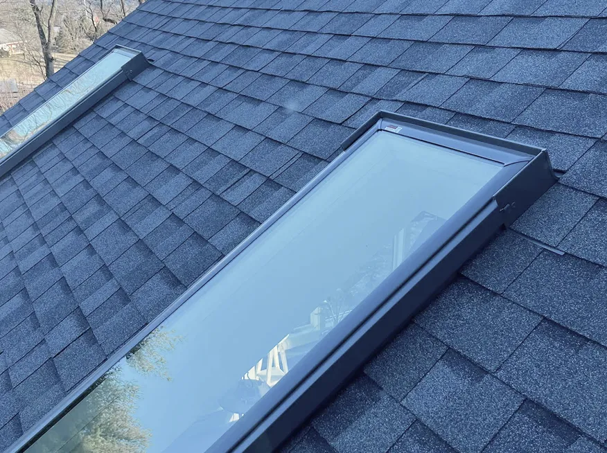 Two rectangular skylight windows are installed on a dark gray shingled roof.
