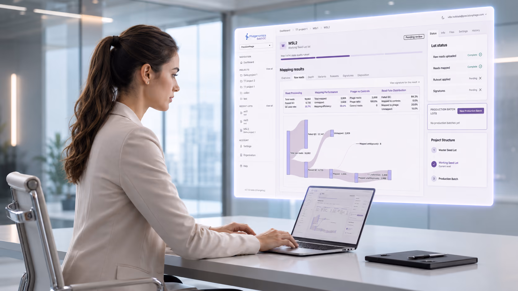 A woman with a ponytail sitting at a desk working on a laptop, viewing a projected screen displaying a mapping results dashboard with charts and data tables in a modern office.