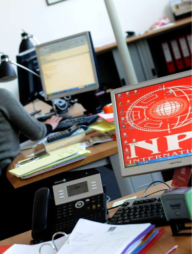 photo du bureau de NPI international avec un ordinateur de bureau au premier plan avec le logo NPI