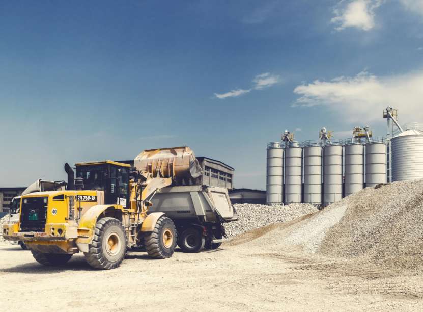 Un bulldozer jaune est garé devant un grand réservoir de stockage.