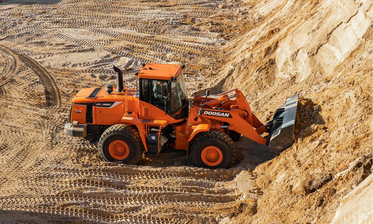 Un gros tracteur orange creuse la terre.