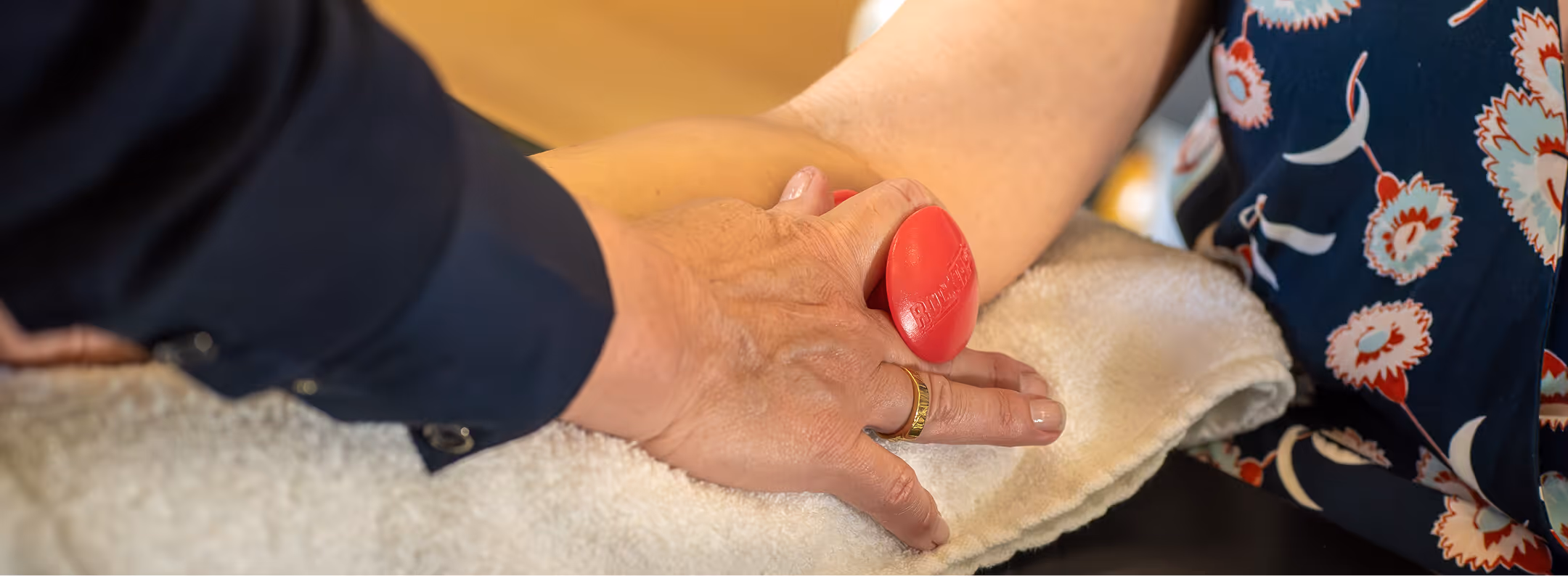 Physical therapist holding patient's arm pressing a red squeeze ball during a physical therapy session in san francisco, ca.