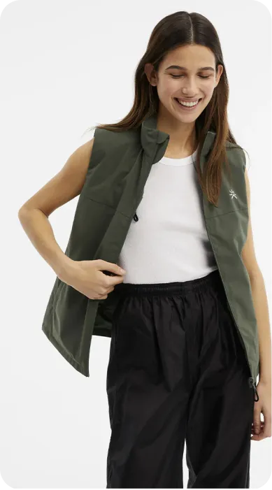 a woman wearing a green vest and black pants