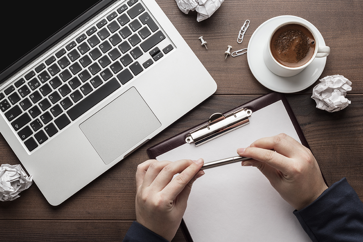 blog writing with a pen paper and laptop
