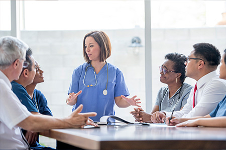 a female clinician leading a discussion with other medical professionals