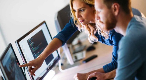 man and woman looking over data on a computer screen