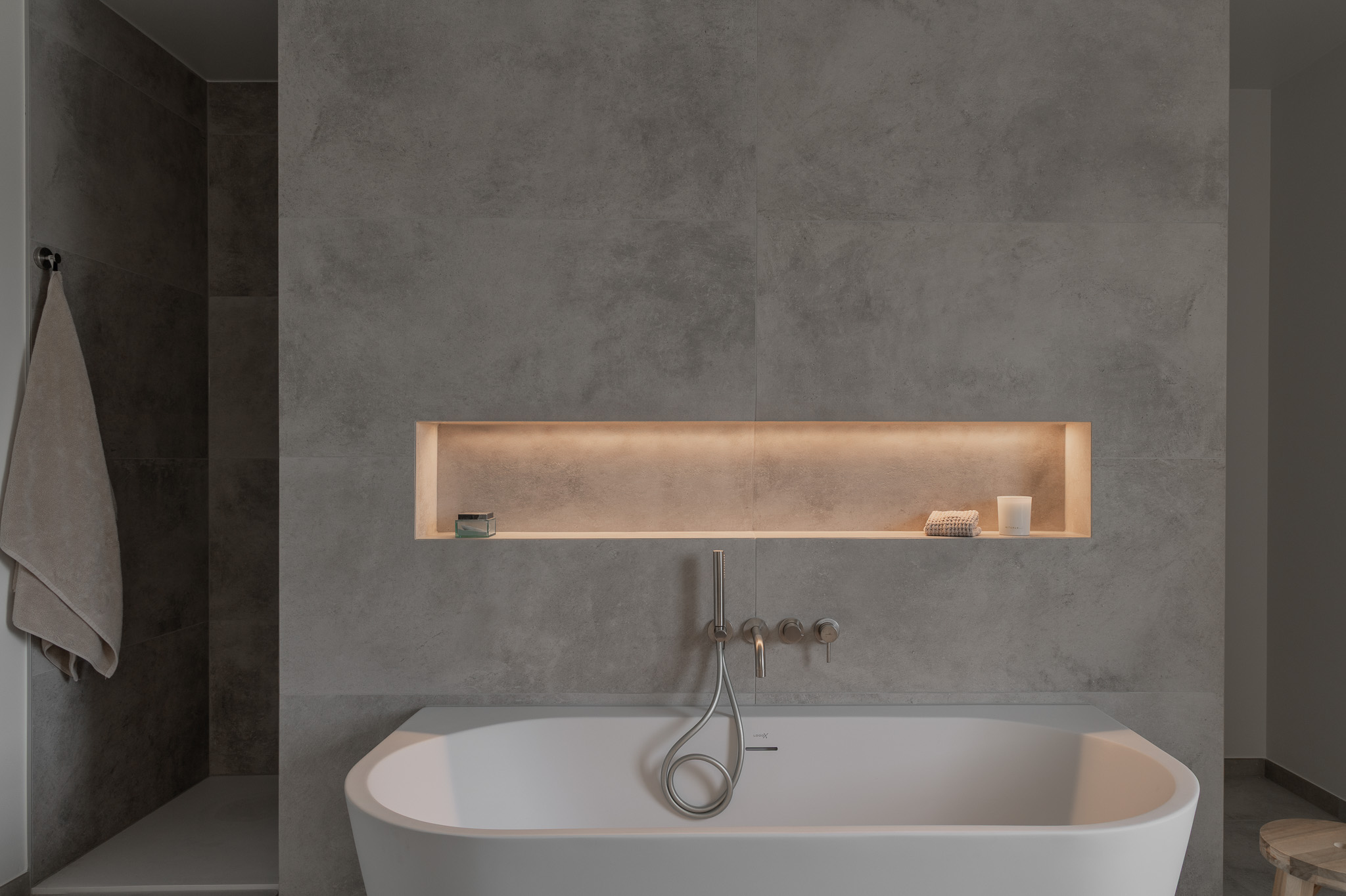 Detailfoto van het nieuwe bad na een volledige badkamerrenovatie. Links en rechts zie je de toegangen naar de douche en het toilet.