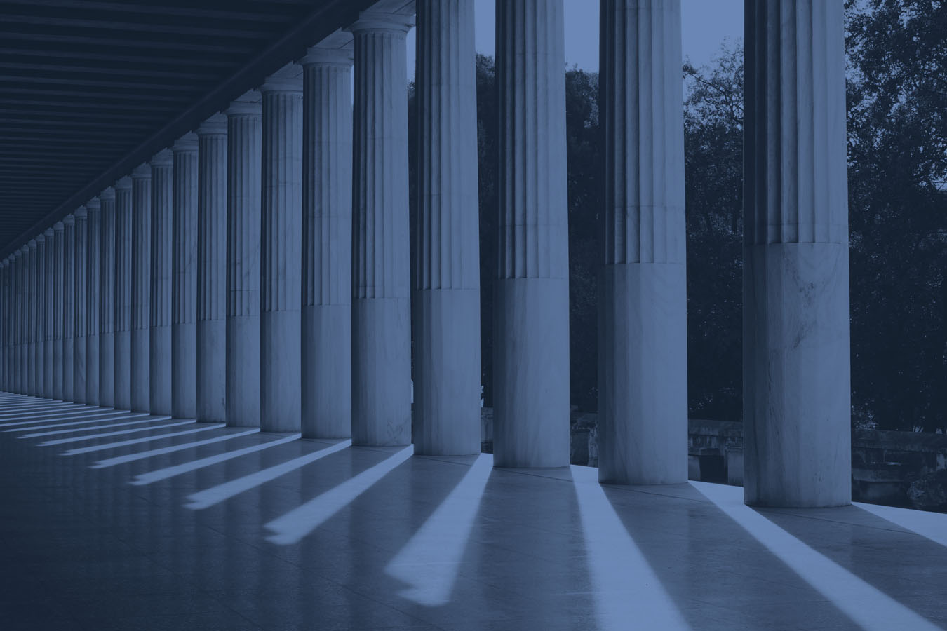 A row of columns with long shadows on the ground.
