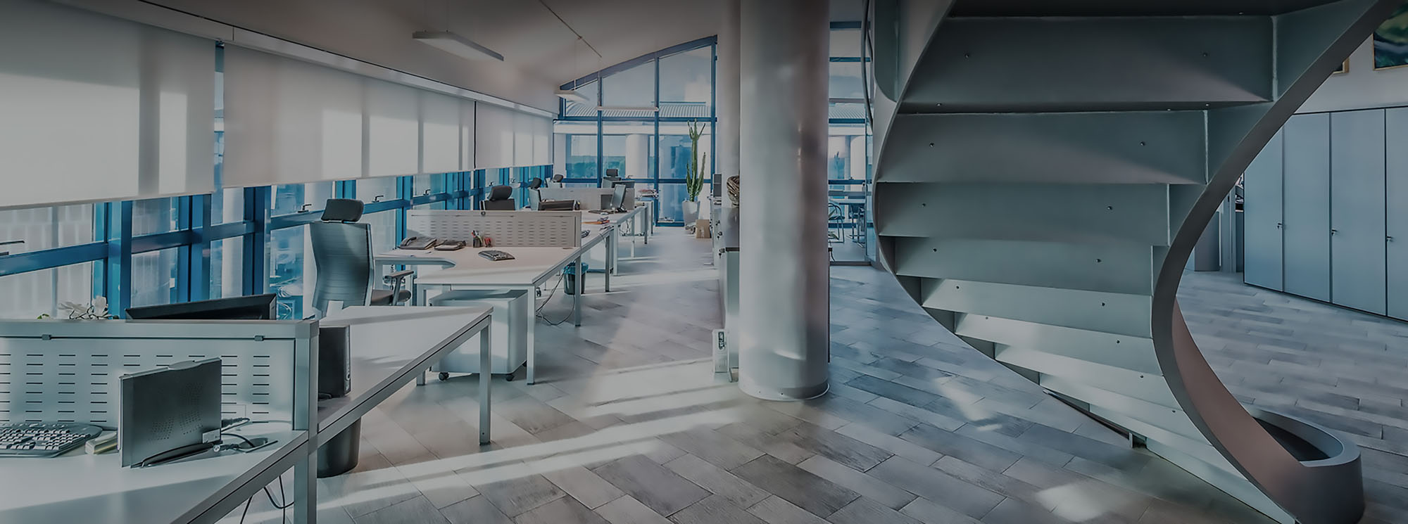 A room with a spiral staircase next to a desk.