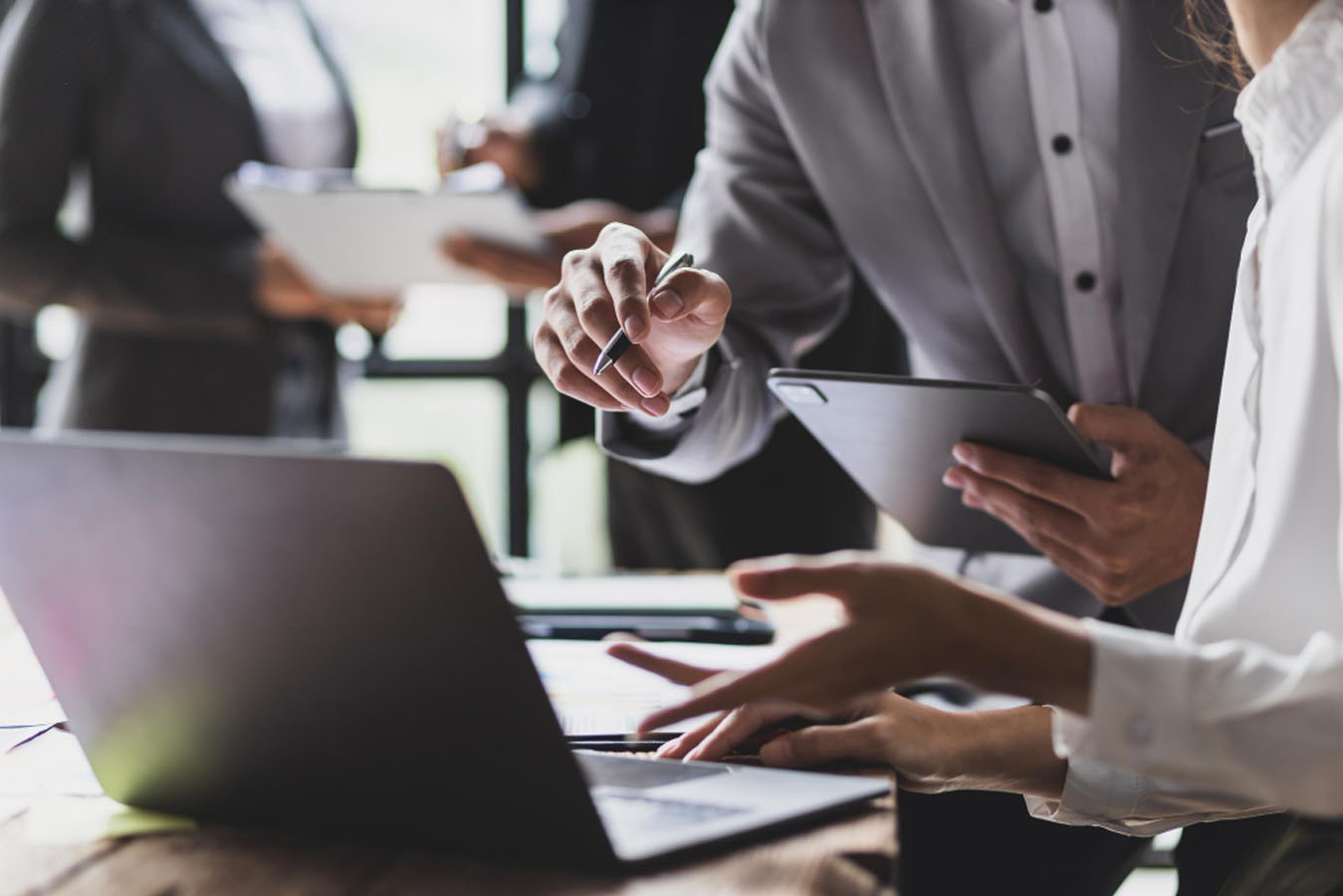 A group of people standing around a laptop computer.
