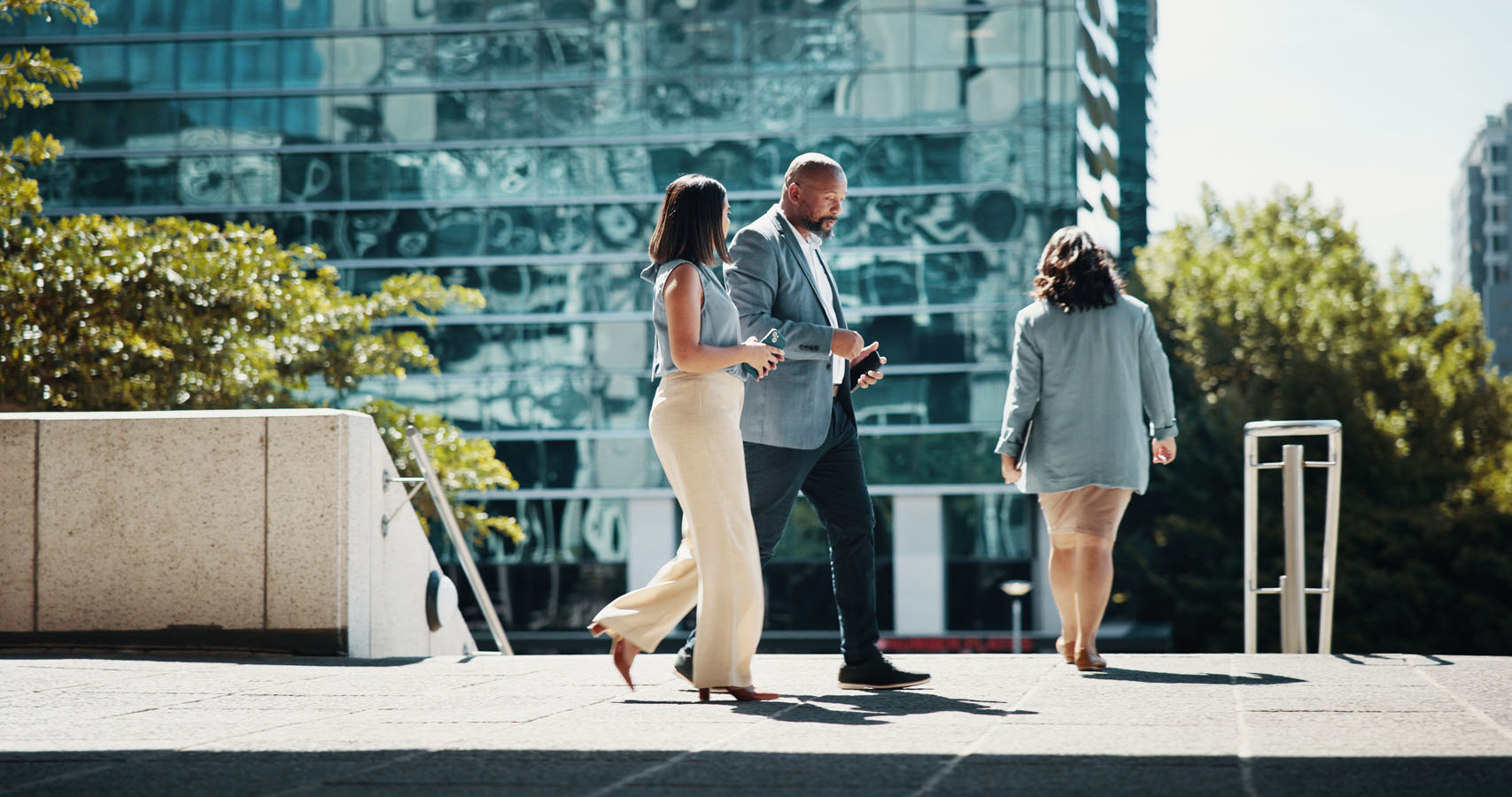 A man and two women walking down a sidewalk.