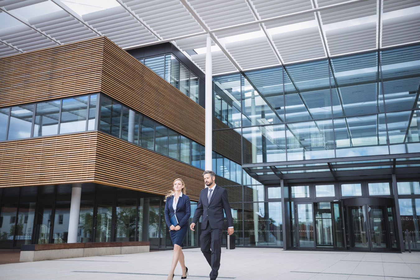 A man and a woman walking in front of a building.