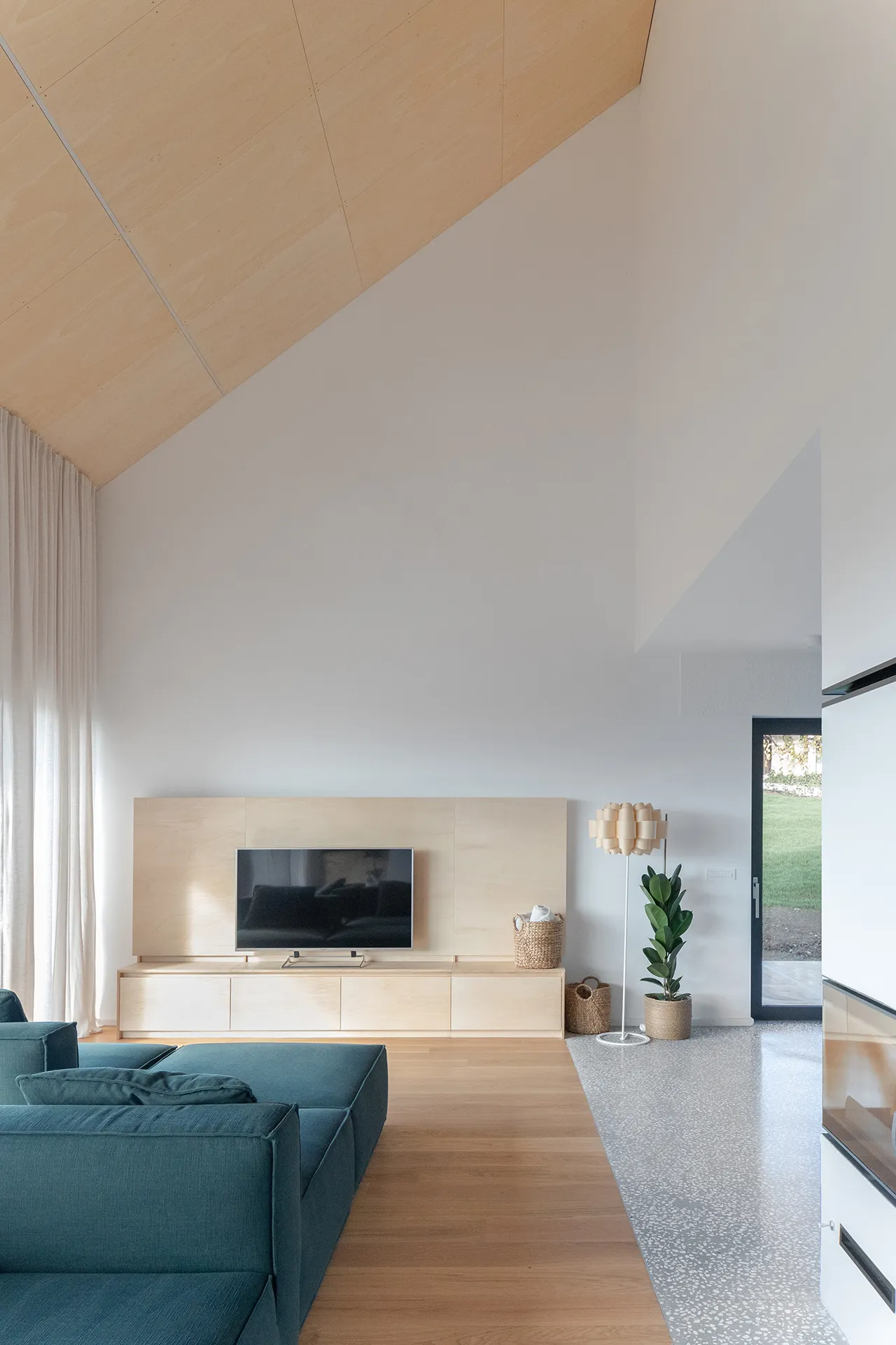 dnevna soba z zofo v središču, ki se na eni strani orientira na kamin, na drugi proti TV in na tretji proti razgledu na pokrajino