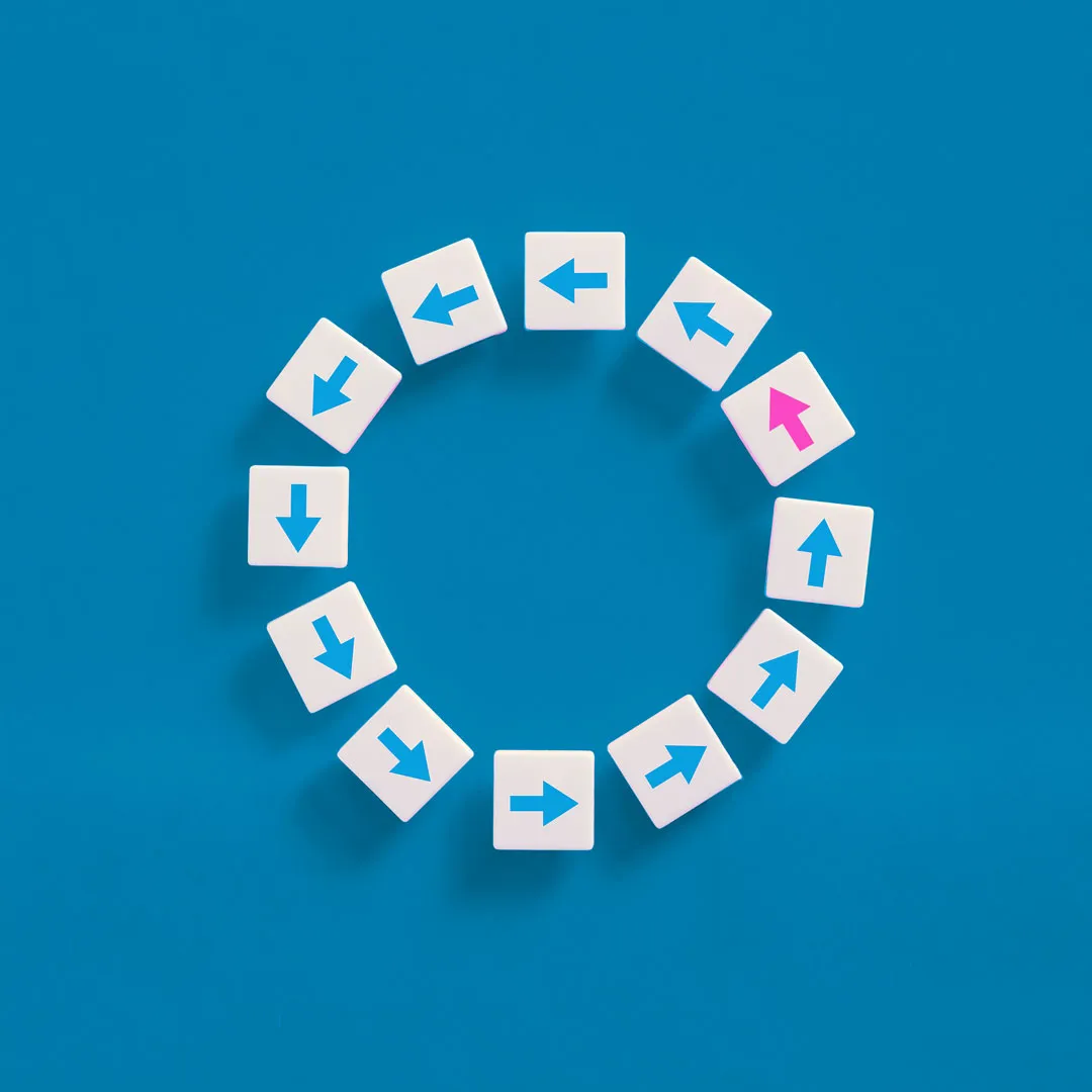 White arrow blocks arranged in a circle with one pink arrow pointing in a unique direction.